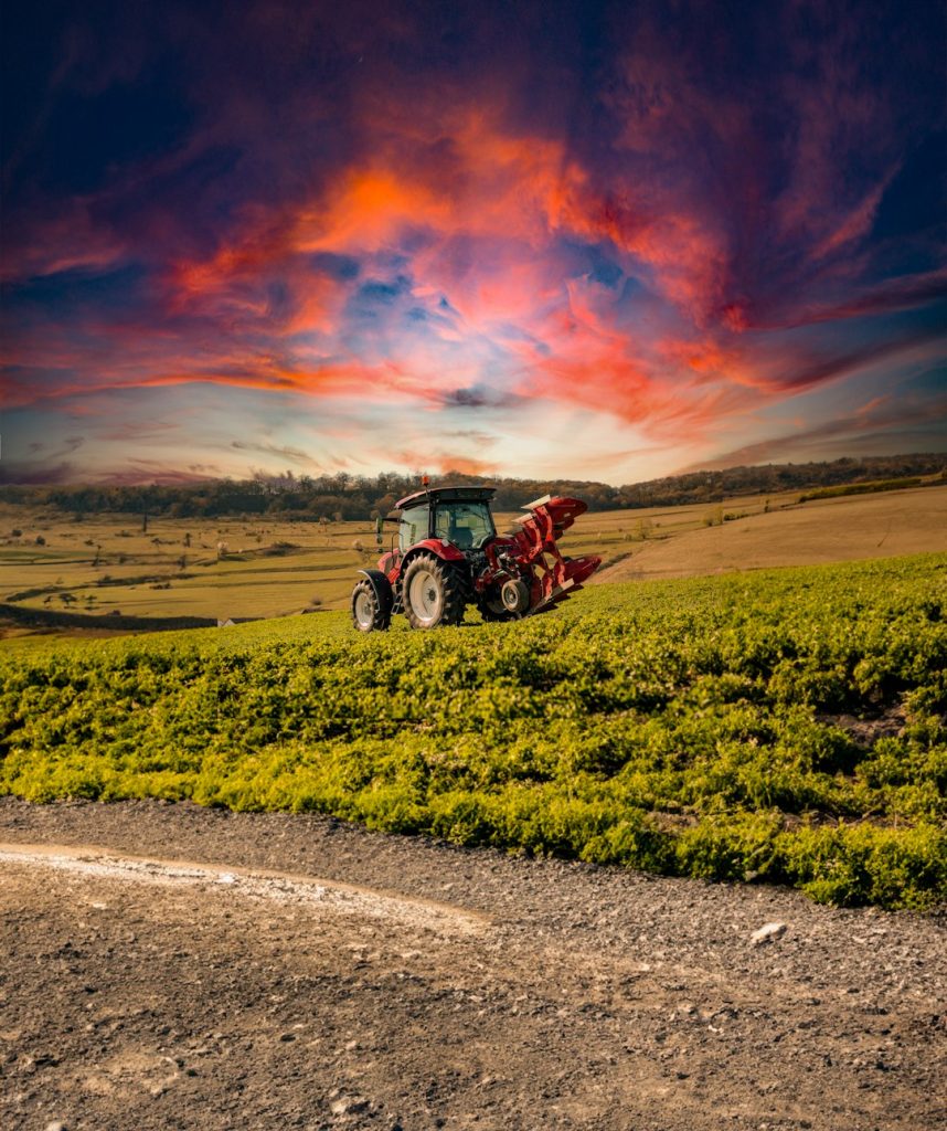 a-tractor-in-a-field-with-a-sunset-in-the-background-ss-o48gpwe